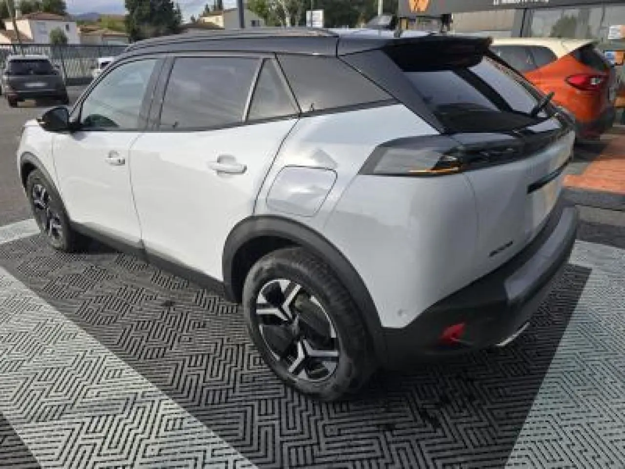 Vue frontale du Peugeot 2008 blanc Okenite avec calandre noire verticale et toit noir brillant.