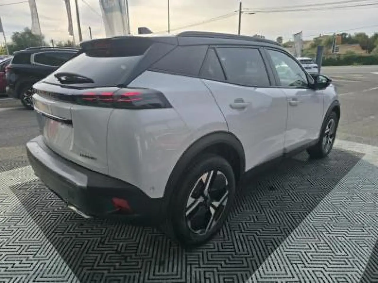 Vue arrière d'un Peugeot 2008 blanc Okenite avec toit noir, feux LED 3 griffes et double sortie d'échappement chromée.