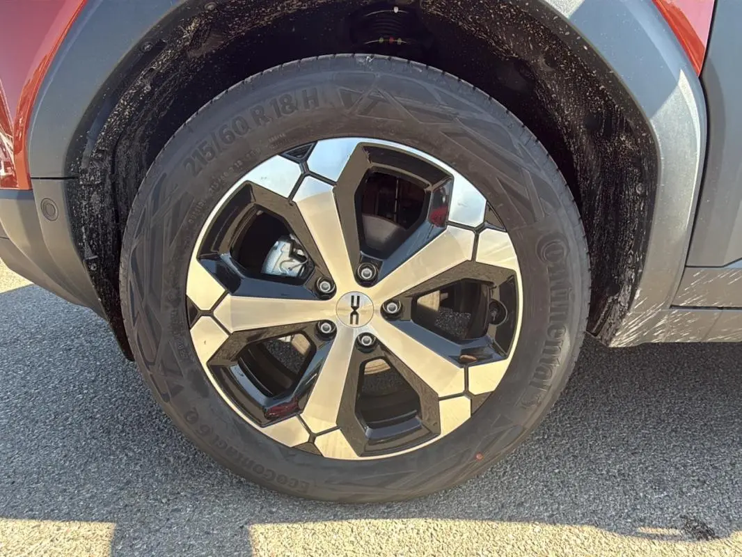 Gros plan sur la jante alliage 18 pouces noire et argent du côté avant droit du Dacia Duster orange 2025.