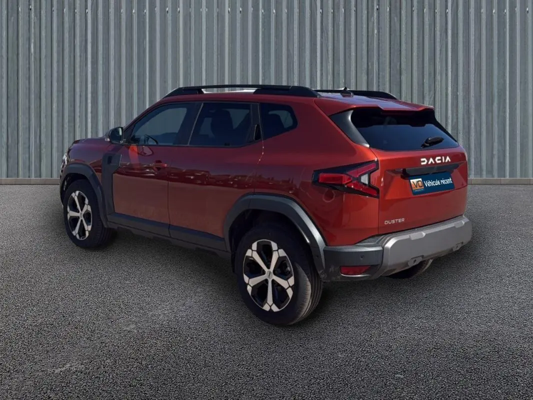 Vue 3/4 arrière droite d'un Dacia Duster orange 2025 avec jantes alliage 18 pouces et vitres surteintées.