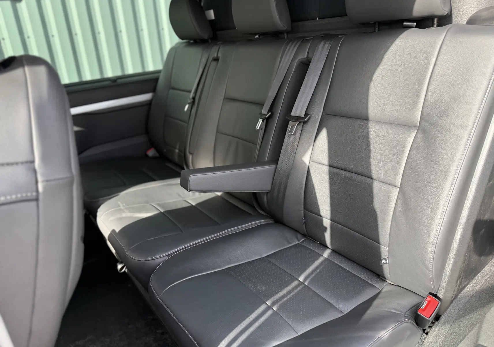 Vue intérieure côté droit des sièges arrière en cuir noir du Citroën Jumpy Cabine Approfondie 2026 avec accoudoir central déployé.