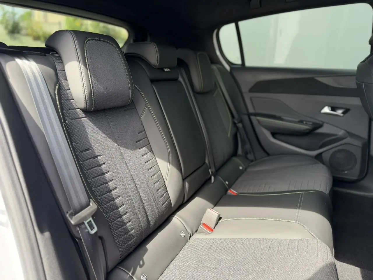 Vue intérieure des sièges arrière en tissu noir avec surpiqûres vert Adamite de la Peugeot 308 NV Hybrid 145 GT.