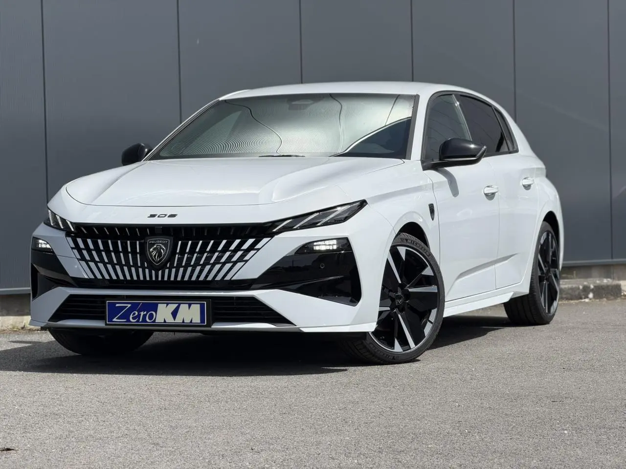 Peugeot 308 NV Hybrid blanc Okenite vue 3/4 avant droit avec calandre noire et jantes alliage bi-tons.