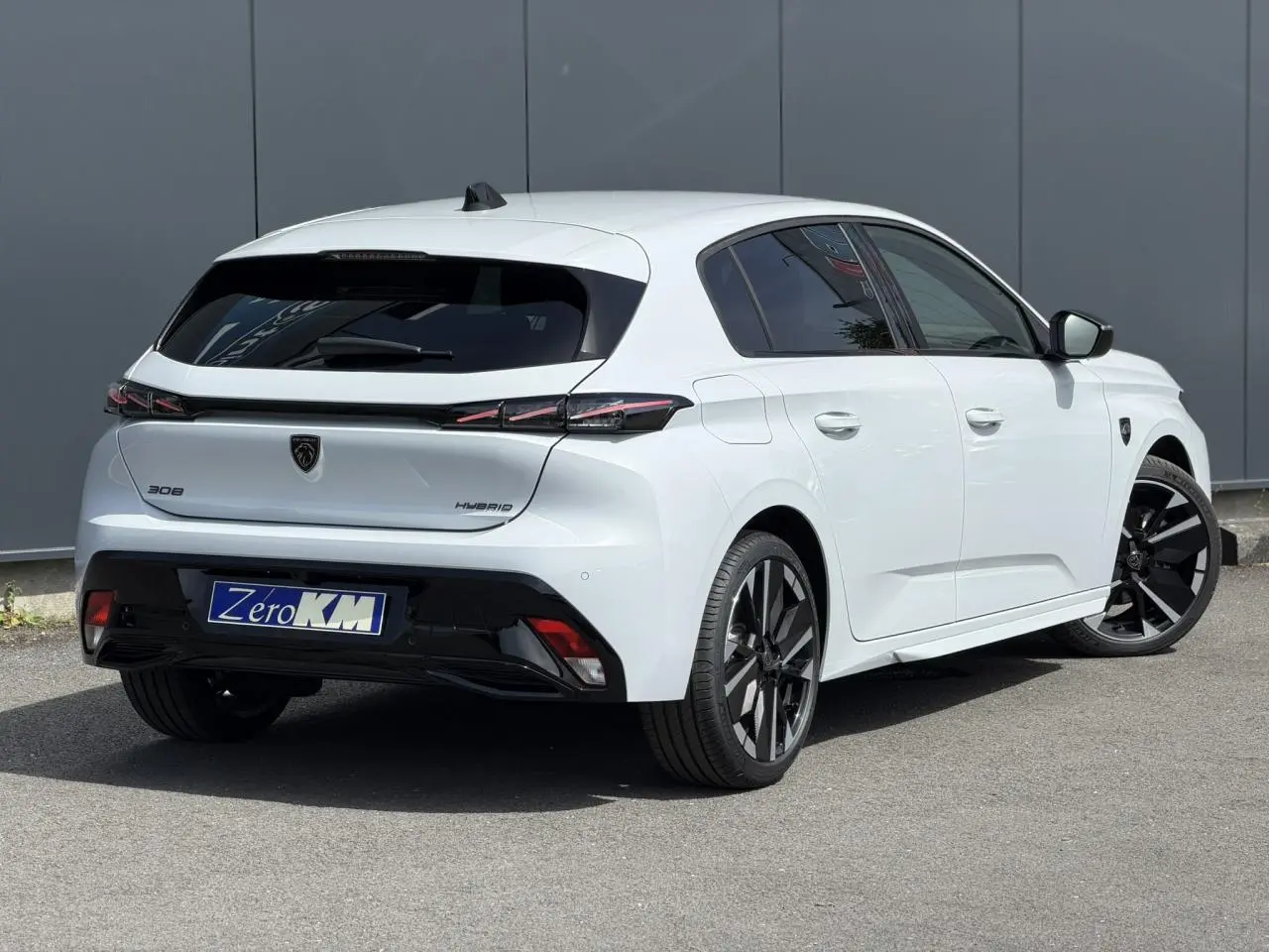 Vue 3/4 arrière droite d'une Peugeot 308 blanche Okenite avec jantes alliage bi-tons et feux arrière LED 3 griffes.