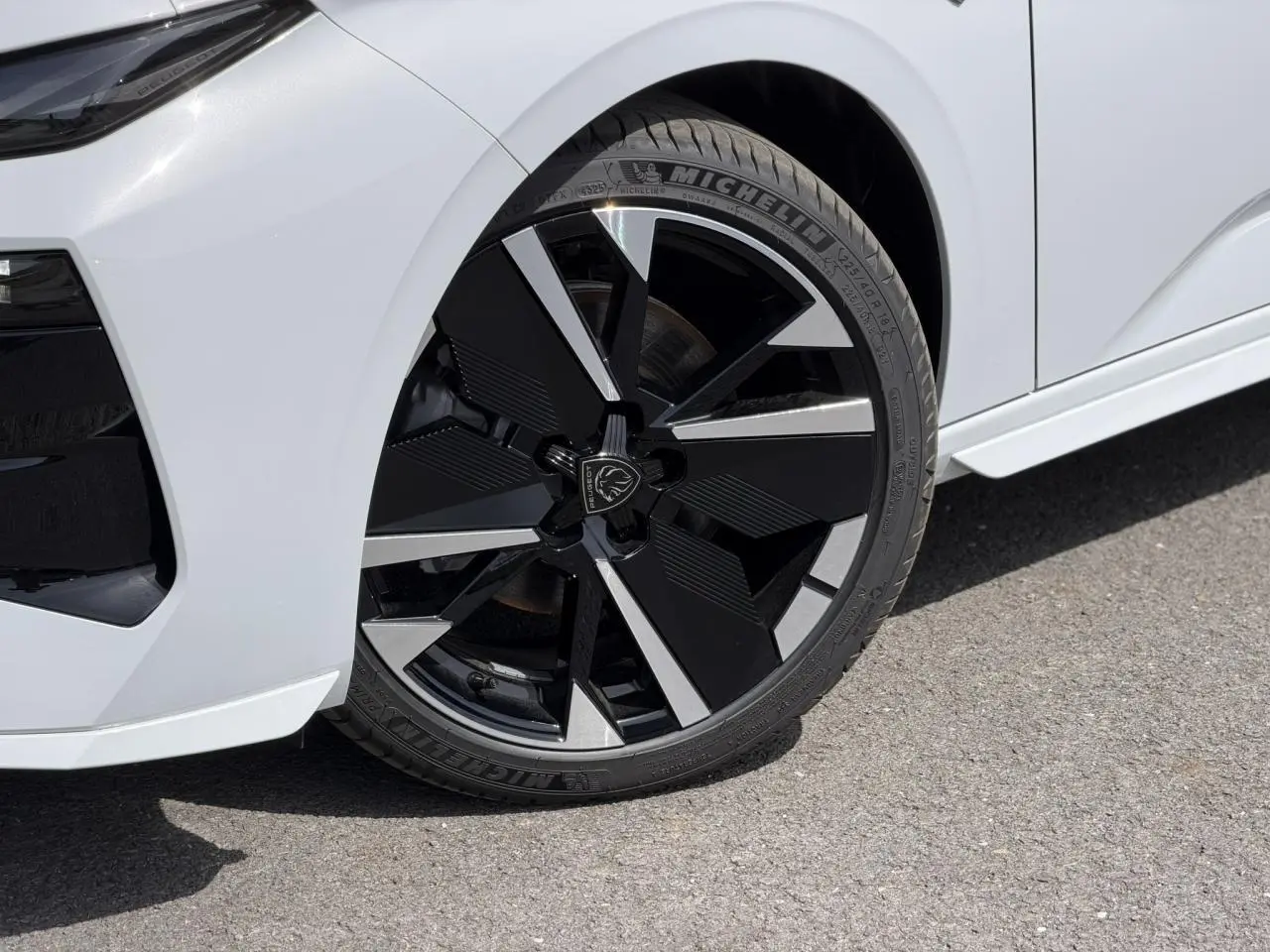 Gros plan sur la roue avant droite noire et argentée de la Peugeot 308 NV Hybrid 145 GT blanc Okenite.
