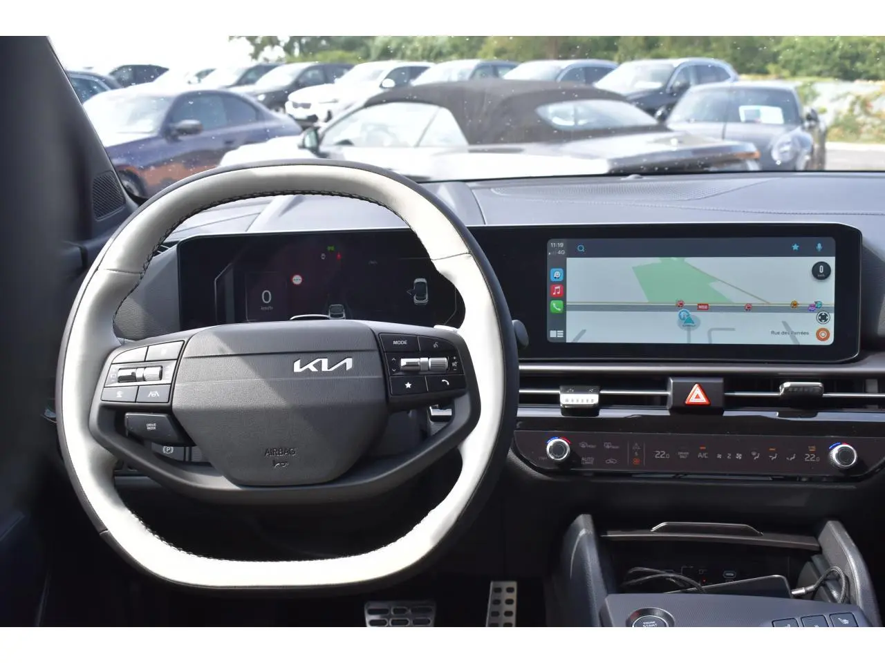 Vue intérieure centrée sur le volant noir et blanc du Kia Sportage 2026 avec écran tactile et tableau de bord digital.