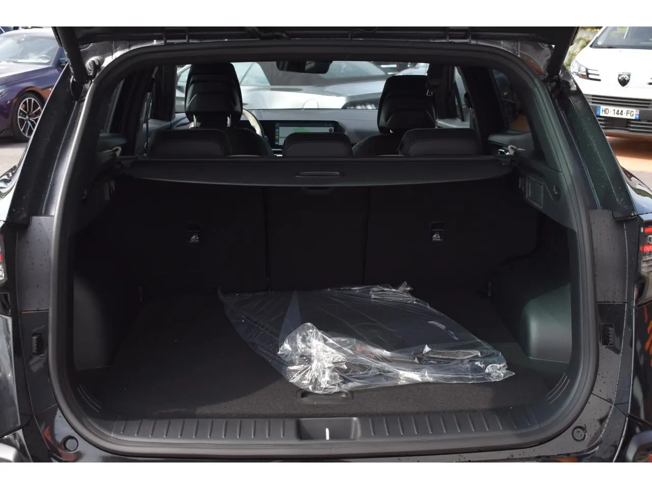 Coffre ouvert d’un KIA Sportage noir 2026, vue arrière montrant l’espace de chargement et la tablette arrière.