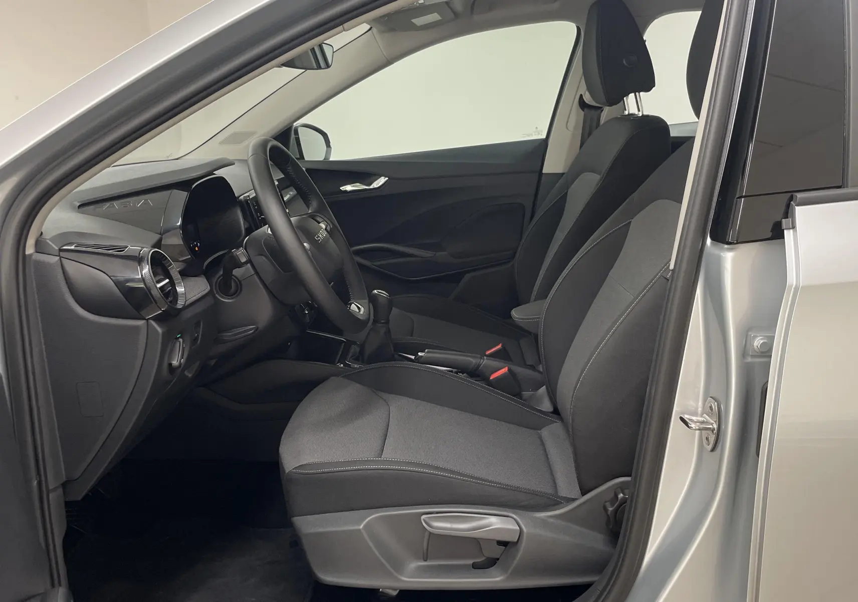 Intérieur côté conducteur d'une Skoda Fabia gris argent 2025, avec sièges tissu noir et tableau de bord moderne.