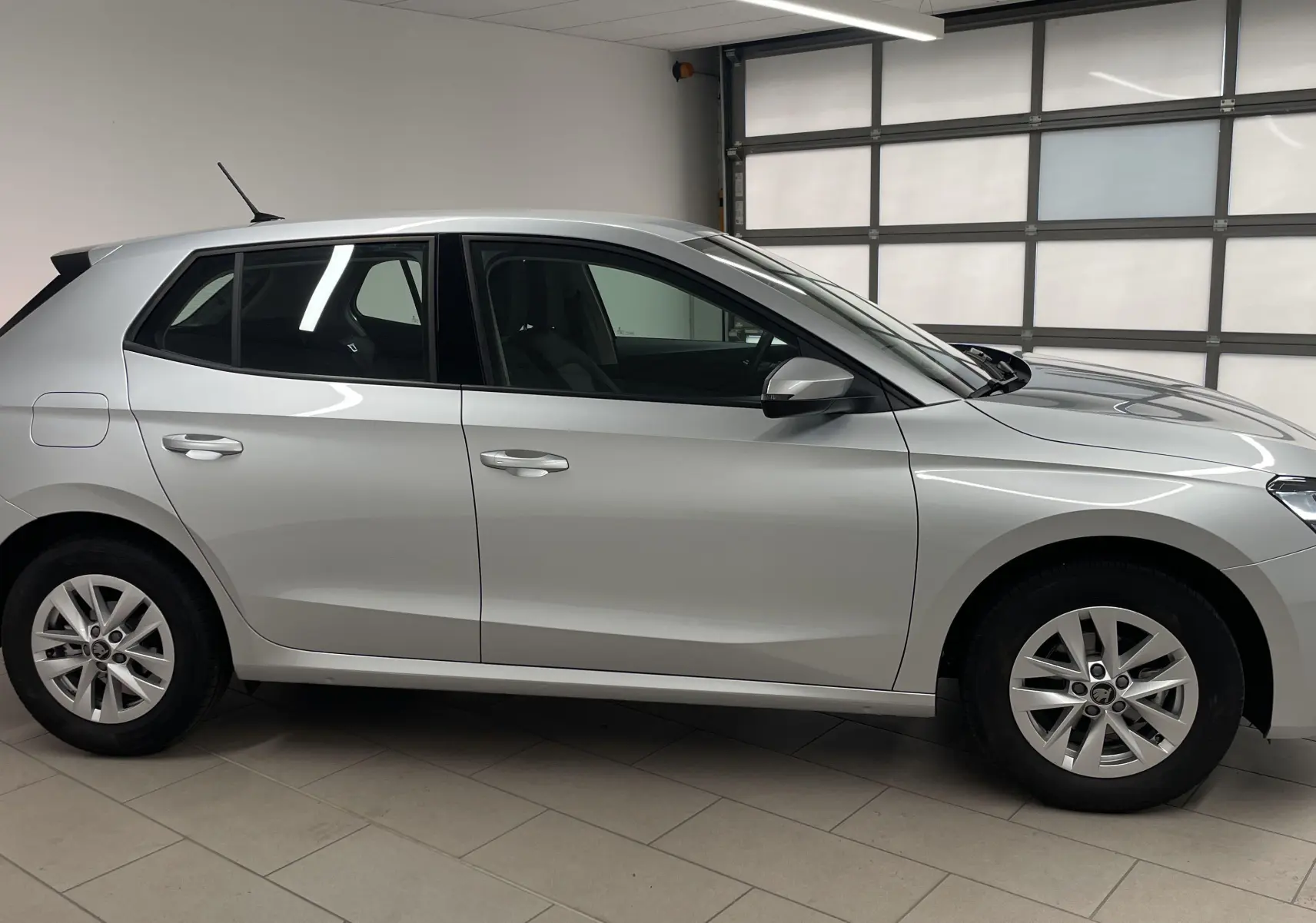 Profil côté gauche d'une Skoda Fabia gris argent 2025 en intérieur, soulignant ses lignes épurées et jantes alliage.