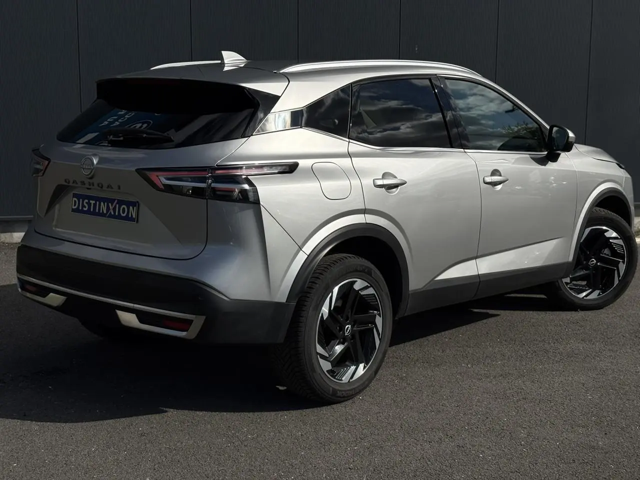Nissan Qashqai 2024 gris foncé en 3/4 arrière droit avec hayon électrique et jantes alliage noires.