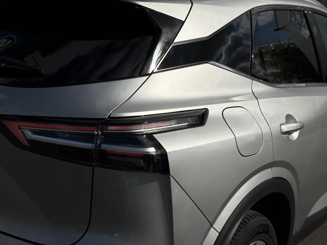Gros plan sur l'arrière droit gris métallisé du Nissan Qashqai 2024 avec feux LED et hayon électrique.