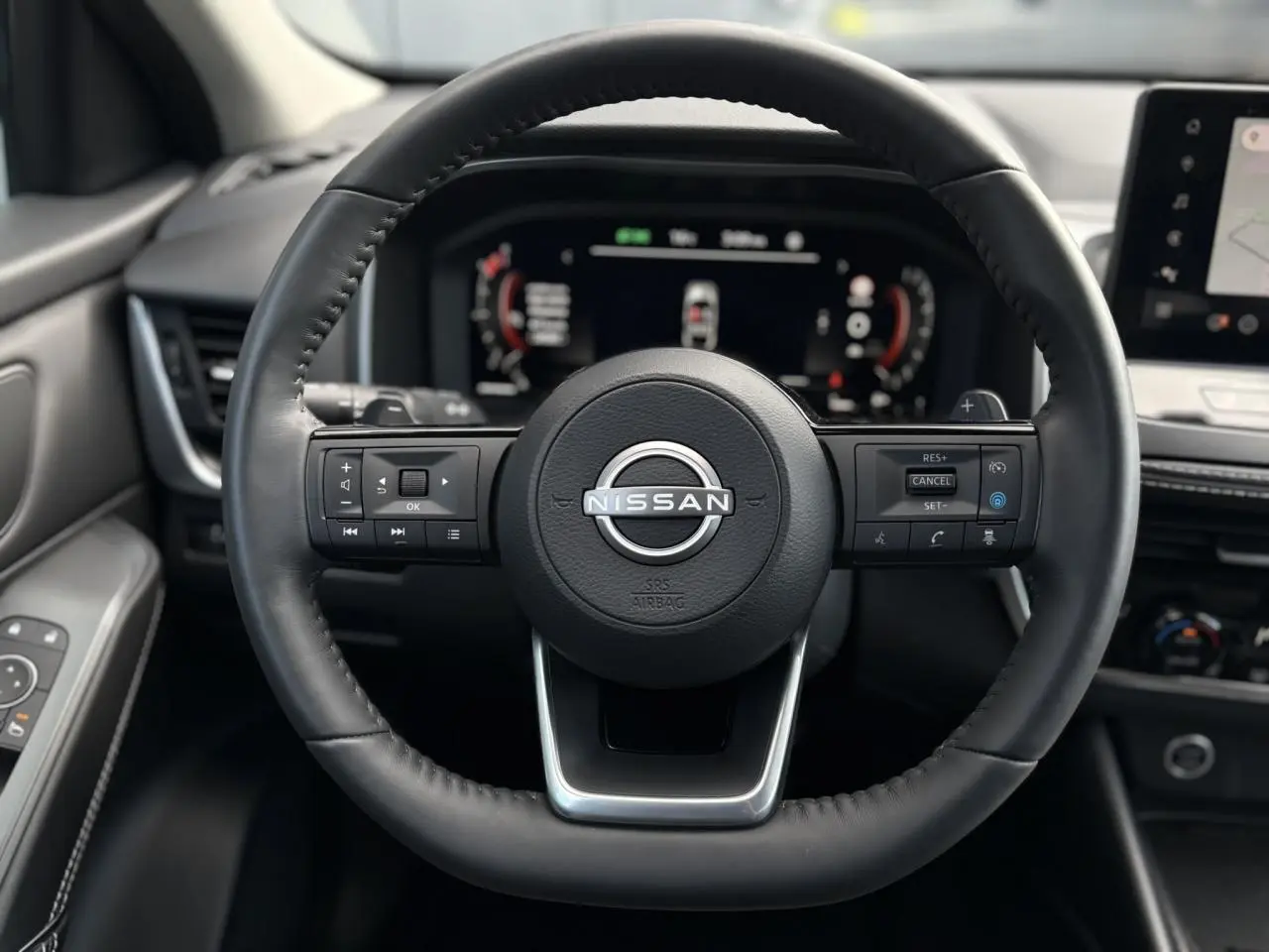 Vue centrée sur le volant cuir noir du Nissan Qashqai 2024 avec commandes intégrées et tableau de bord numérique.