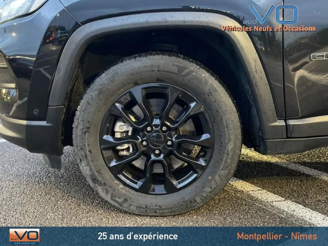 Gros plan sur la roue avant gauche noire en alliage 18 pouces du Jeep Compass noir 2021 avec logo central visible.