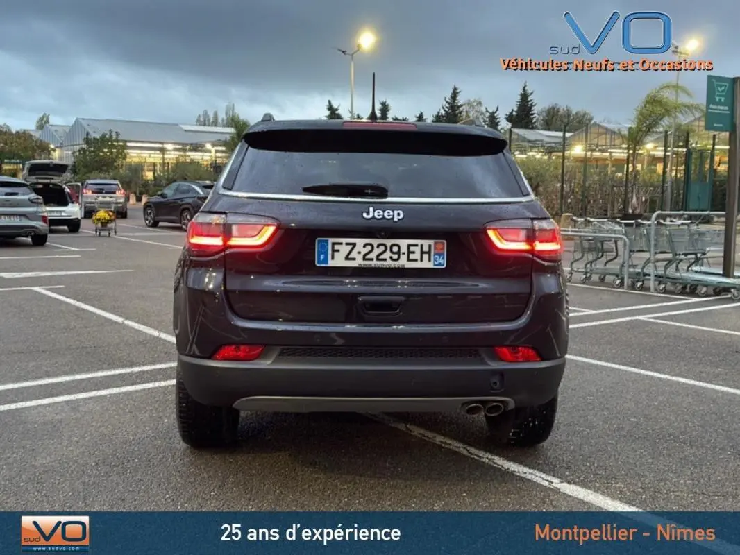 Vue arrière d'un Jeep Compass noir 2021 avec feux allumés et double sortie d'échappement visible en parking.