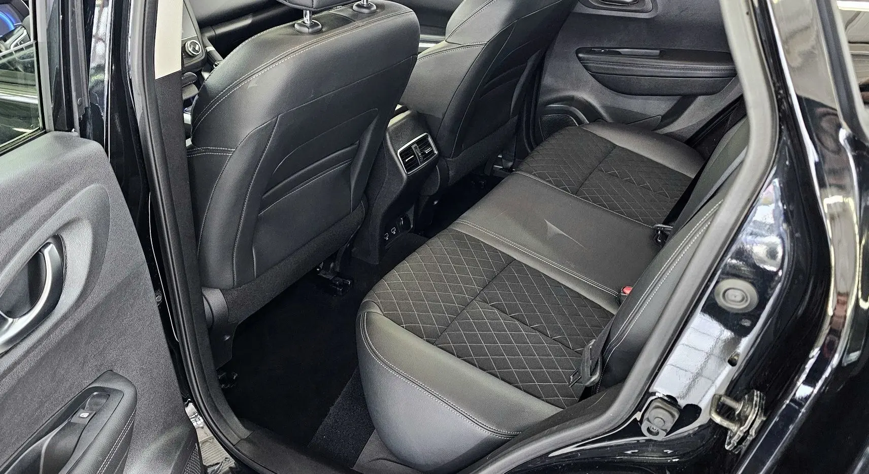 Vue intérieure arrière côté gauche du Renault Kadjar noir 2021, sièges en cuir noir avec surpiqûres et aérateurs centraux.