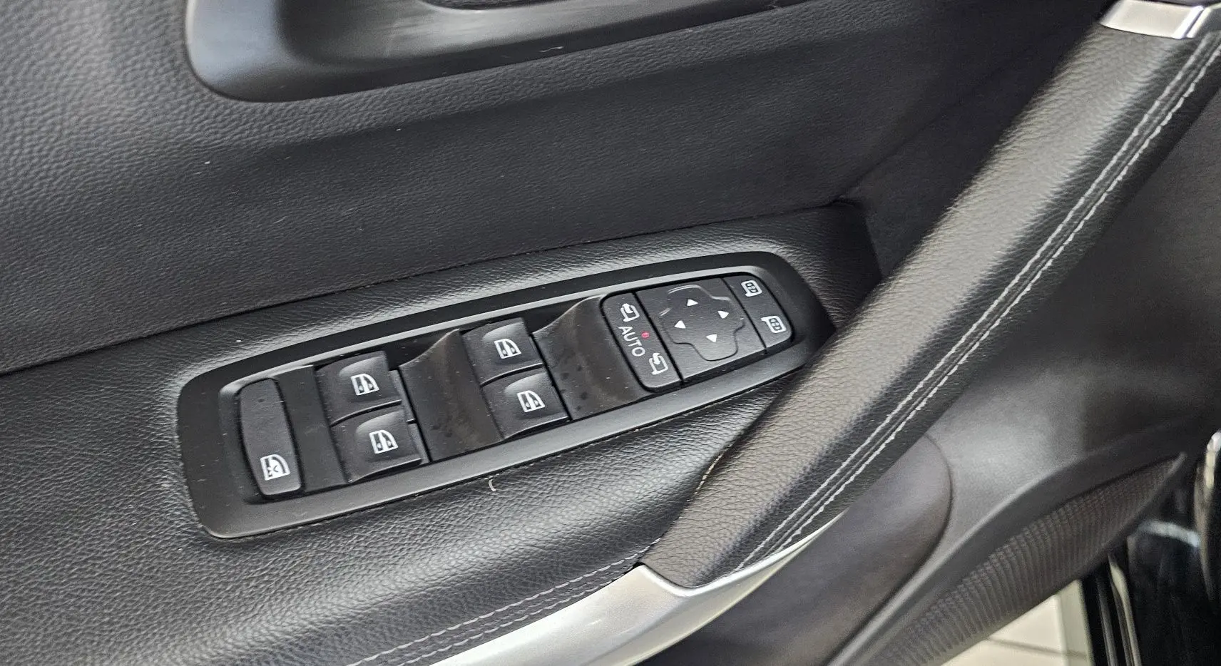 Détail des commandes de lève-vitres et réglage des rétroviseurs sur la portière côté gauche d'un Renault Kadjar noir.