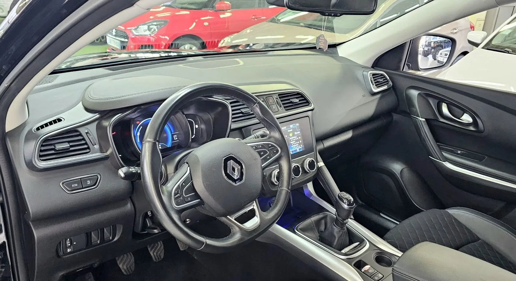 Intérieur du Renault Kadjar noir 2021 vu côté conducteur, volant cuir, tableau de bord avec écran tactile et boîte manuelle.