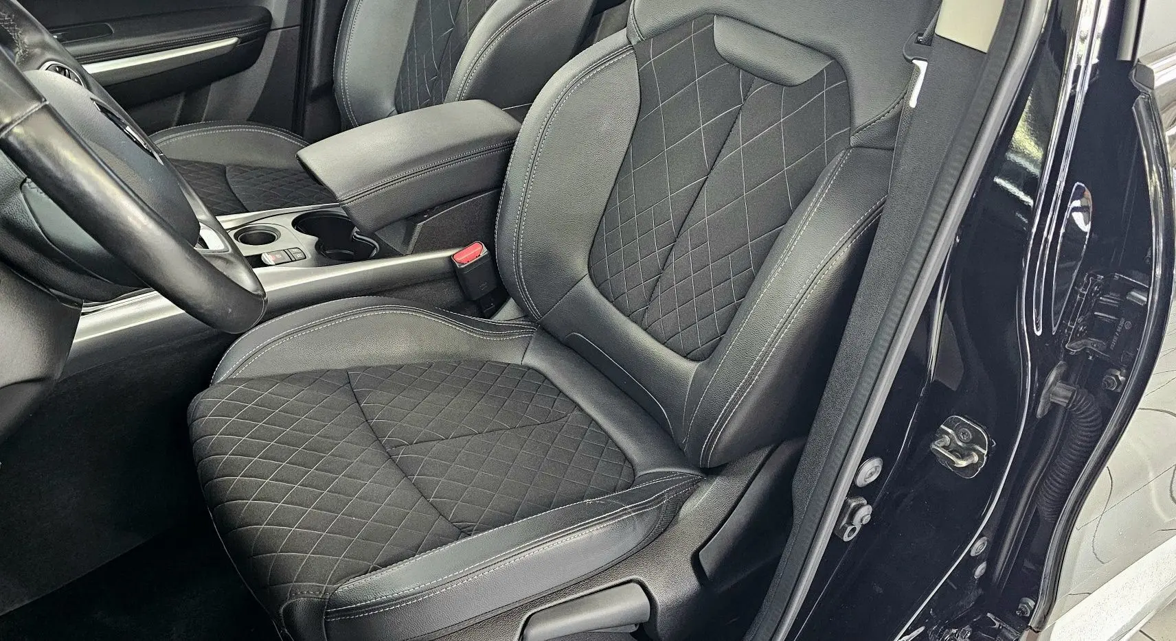 Vue intérieure côté conducteur du Renault Kadjar 2021 noir, montrant le siège en cuir noir matelassé et le volant.