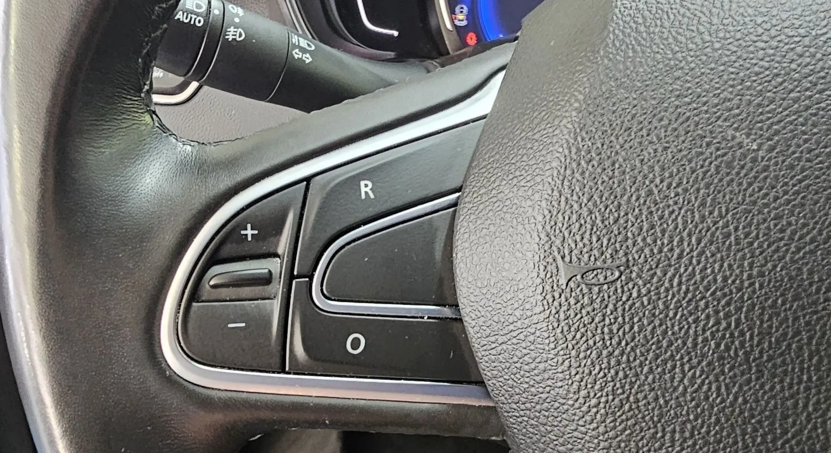 Gros plan sur les commandes de régulateur de vitesse au volant cuir noir du Renault Kadjar 2021 intense.