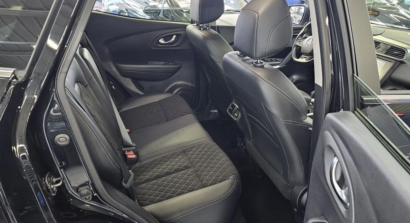 Vue intérieure côté gauche arrière du Renault Kadjar noir 2021, sièges en cuir noir avec surpiqûres et tableau de bord visible.