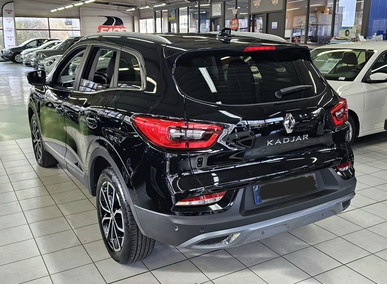 Vue 3/4 arrière du Renault Kadjar noir 2021 en showroom, avec feux arrière et jantes biton visibles.