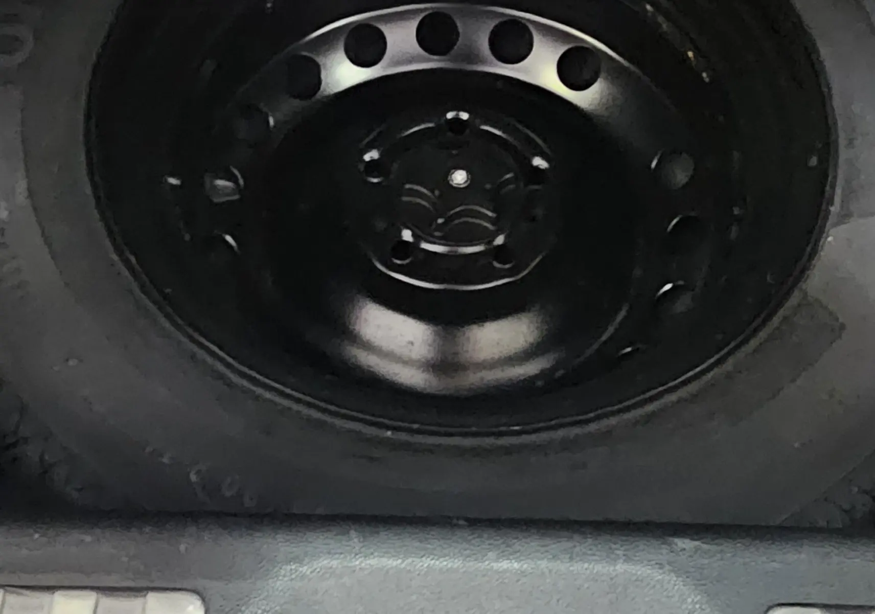 Gros plan sur la roue de secours noire et le cric dans le coffre du Renault Kadjar 2021 intense.