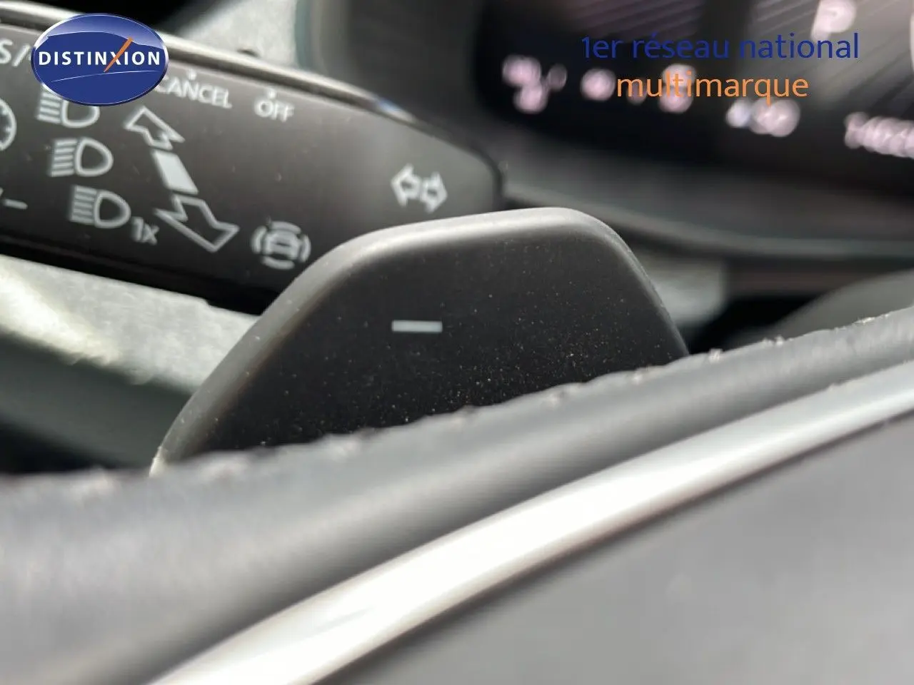 Gros plan sur la palette de changement de vitesse au volant d’une Skoda Scala blanc glacier, intérieur gris noir.