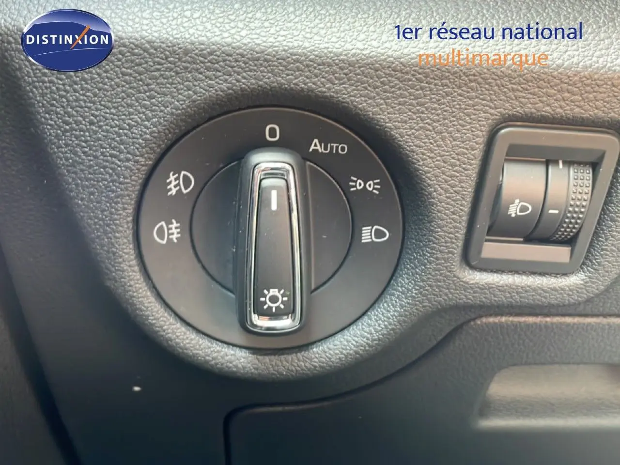 Gros plan sur le bouton de commande des phares dans l'habitacle noir du Skoda Scala blanc Glacier 2025.