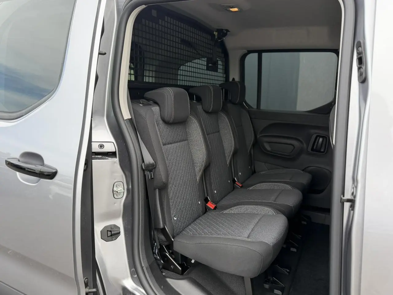 Vue intérieure côté droit des trois sièges individuels arrière du Peugeot Rifter gris acier avec porte coulissante ouverte.
