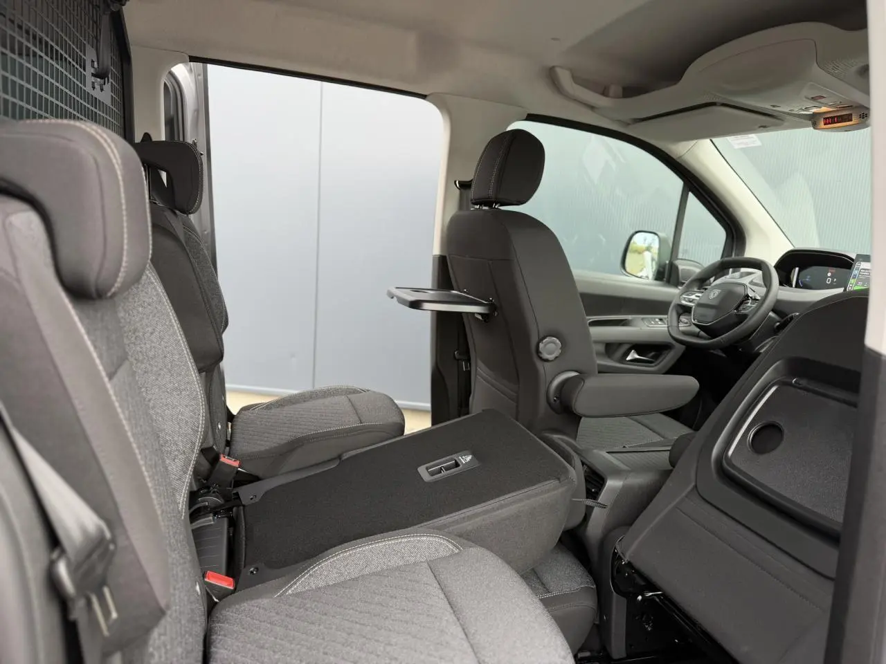 Vue intérieure côté droit du Peugeot Rifter gris acier 2026, montrant les sièges individuels arrière et le poste de conduite.