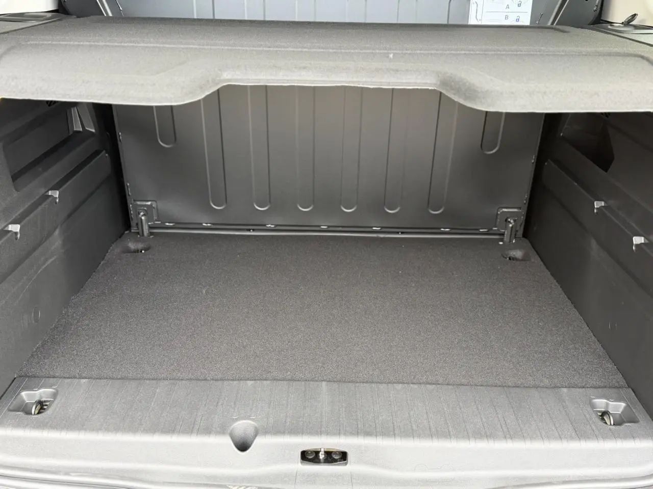 Coffre spacieux du Peugeot Rifter gris acier, vue intérieure arrière avec cache-bagages déployé.