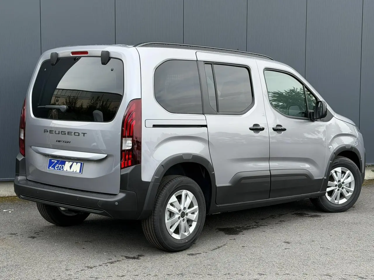 Peugeot Rifter gris acier vu en 3/4 arrière droit, avec vitres arrière surteintées et jantes alu 16 pouces.