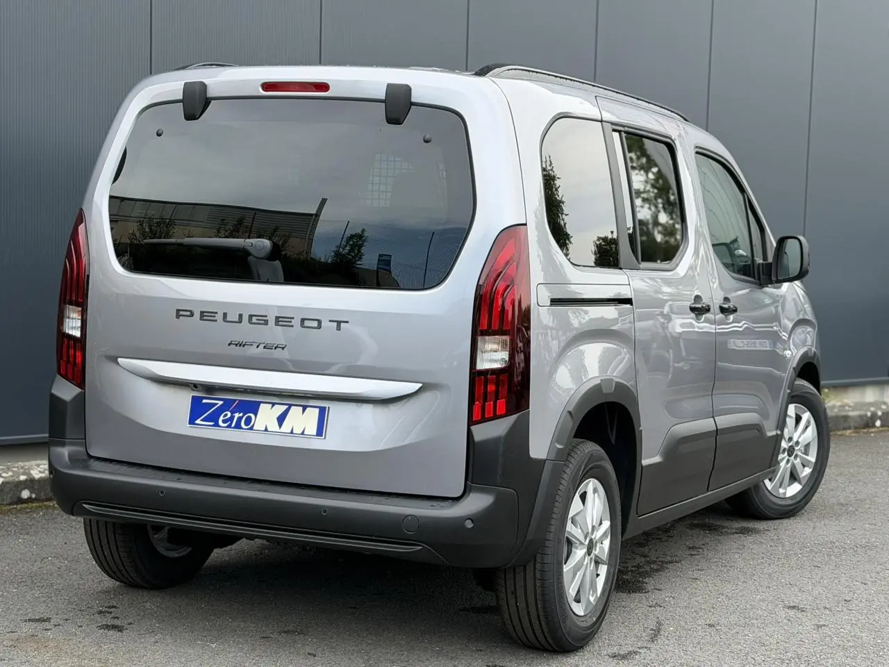 Vue 3/4 arrière droite du Peugeot Rifter gris acier 2026 avec portes latérales coulissantes et feux arrière LED verticaux.