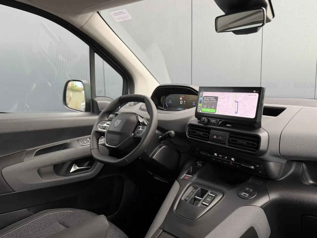 Vue intérieure côté conducteur du Peugeot Rifter gris acier 2026, avec tableau de bord numérique et écran tactile GPS.