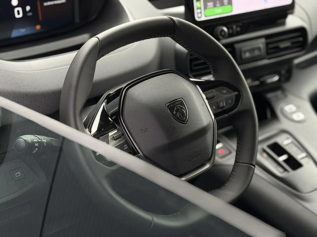Gros plan sur le volant cuir noir du Peugeot Rifter 2026 avec commandes intégrées et tableau de bord numérique partiel.