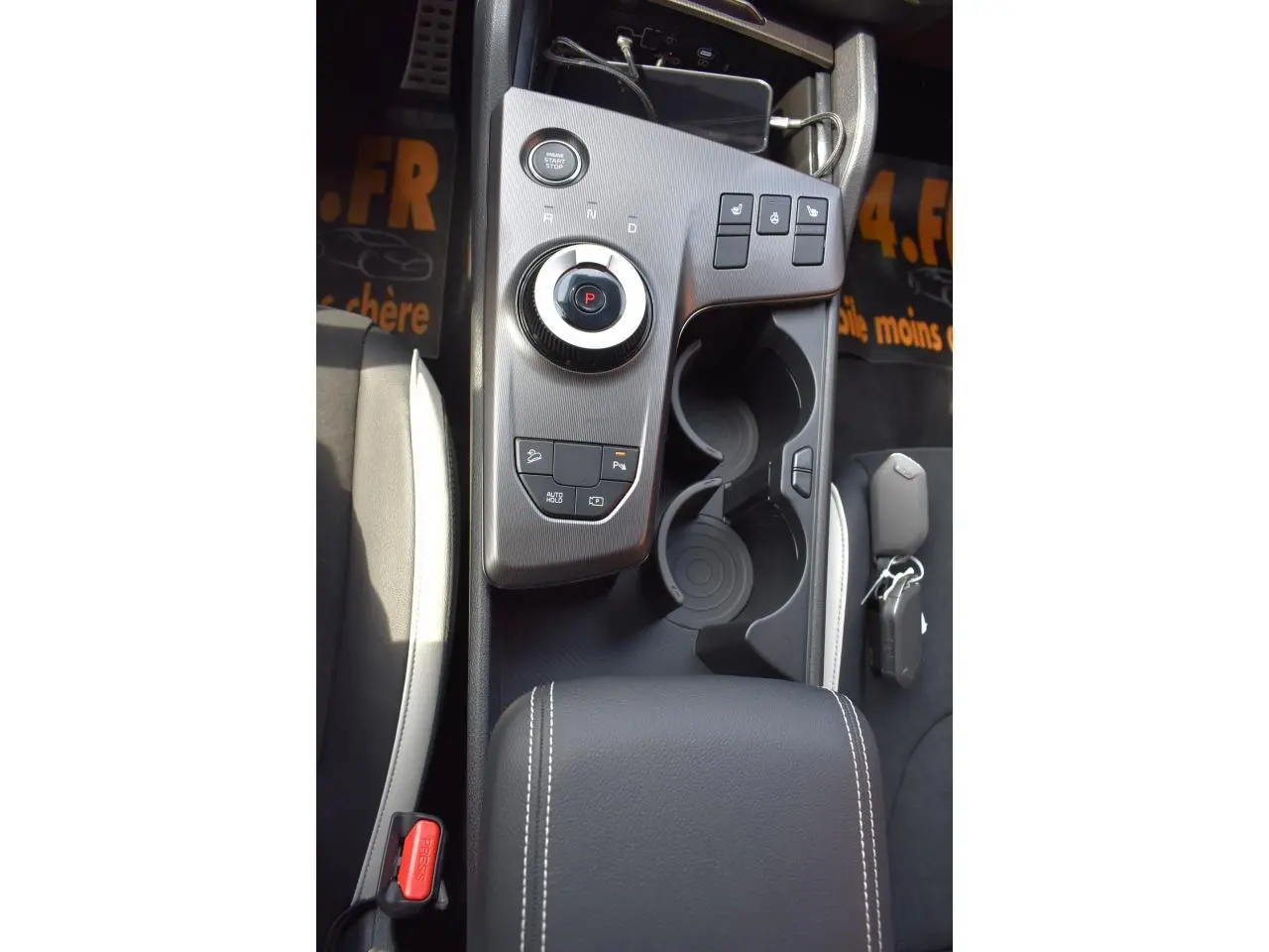 Vue plongeante sur la console centrale noire du Kia Sportage hybride 2026 avec molette de sélection et porte-gobelets.