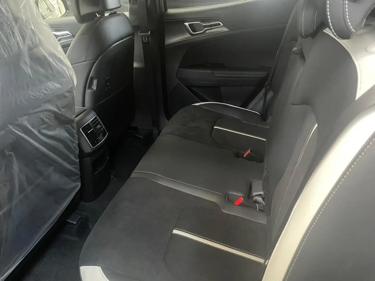Vue intérieure côté droit des sièges arrière noirs avec surpiqûres blanches du Kia Sportage Hybride 2026 GT-Line.