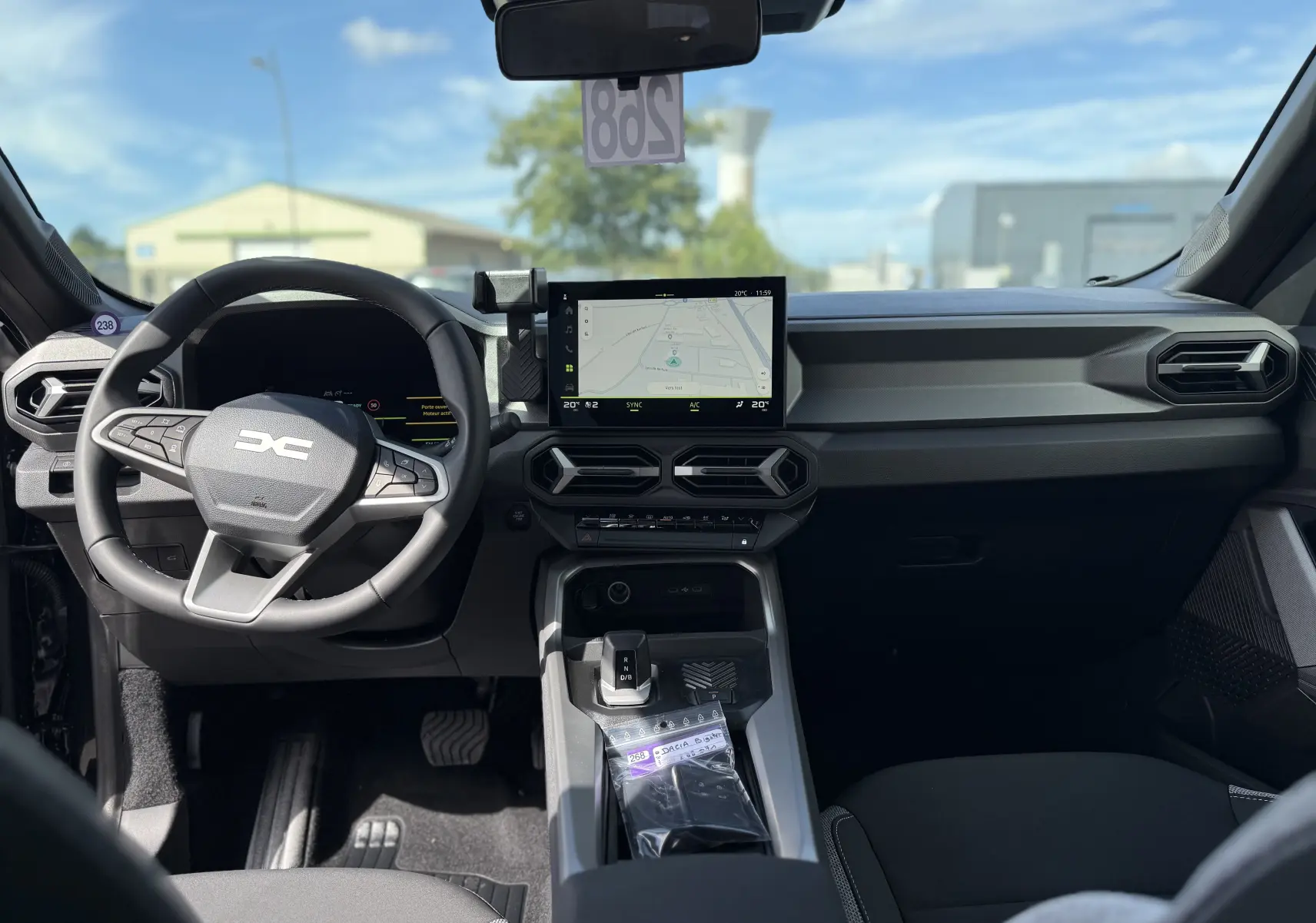 Vue intérieure avant du Dacia Bigster Hybrid 155 Journey noir nacré, avec tableau de bord moderne et écran tactile central.