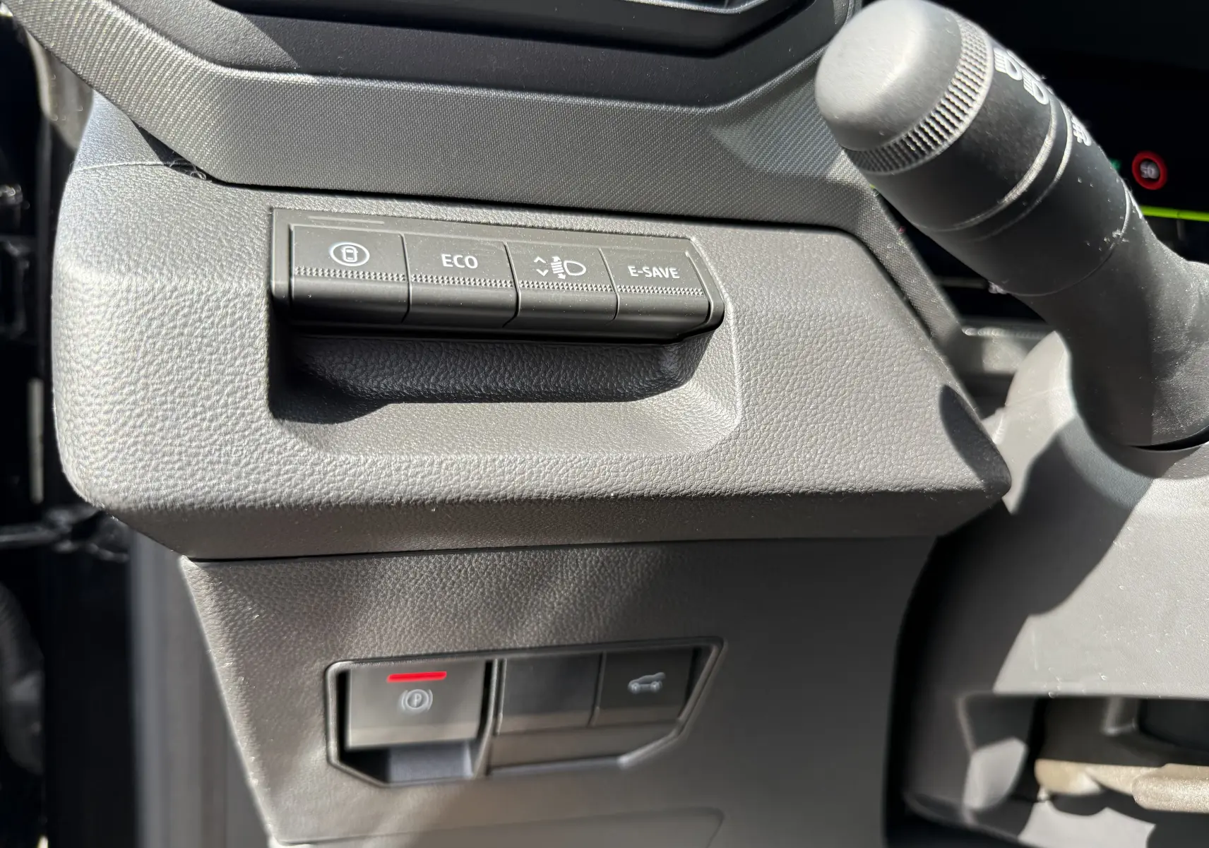 Détail intérieur du tableau de bord côté gauche du Dacia Bigster Hybrid 155 Journey 2026, boutons de contrôle et levier.