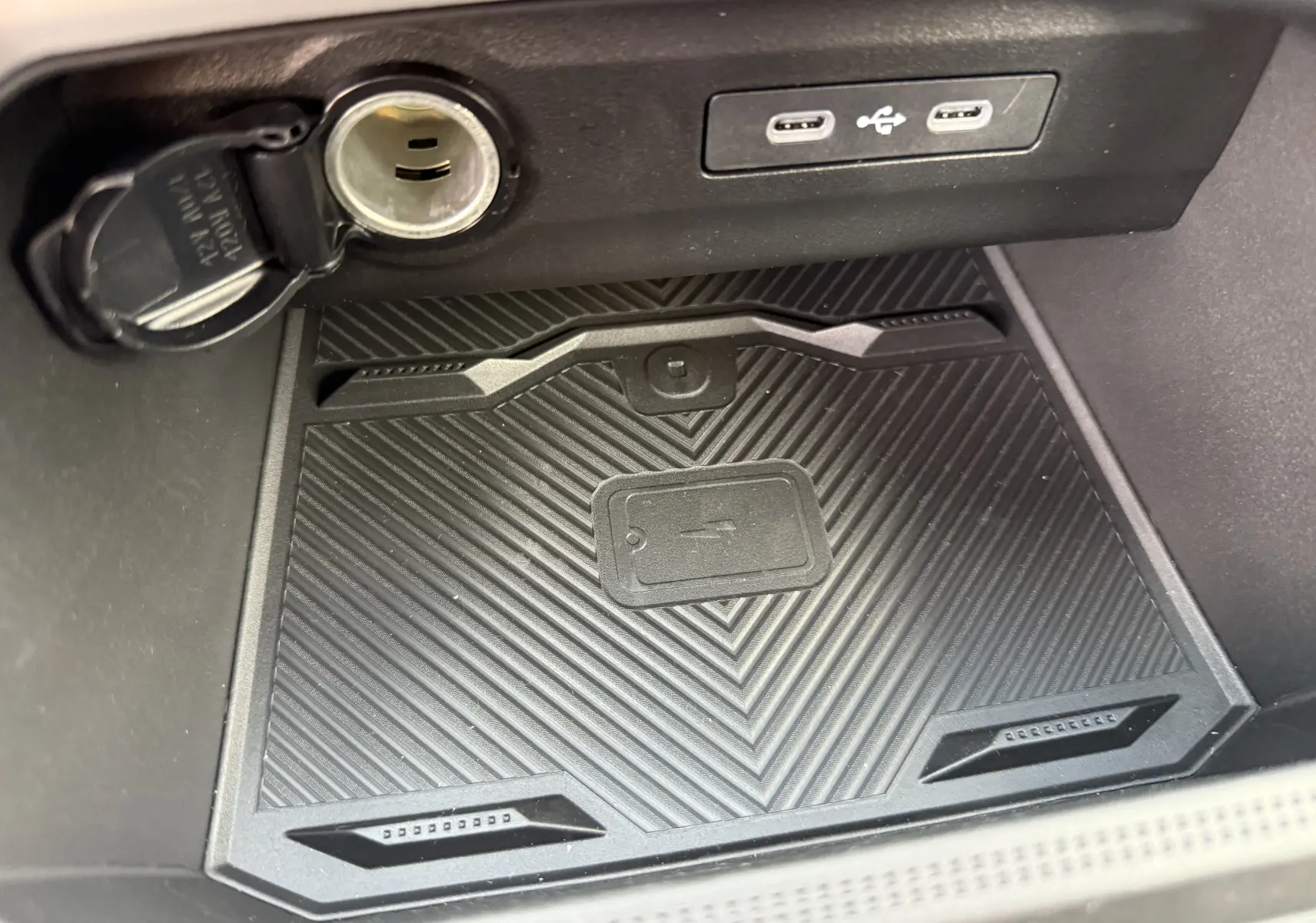 Gros plan intérieur sur le compartiment de recharge sans fil et prises USB du Dacia Bigster Hybrid 155 Journey noir nacré.