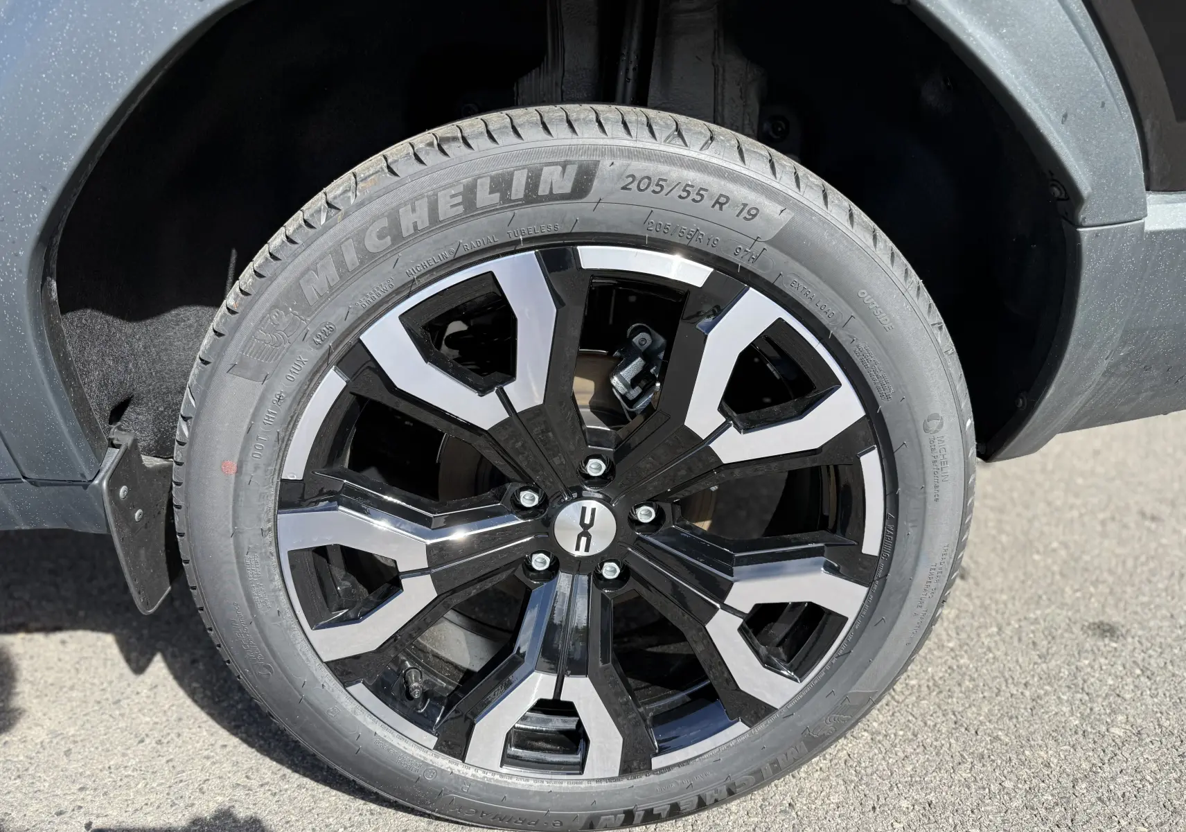 Gros plan sur la roue avant droite du Dacia Bigster noir nacré, jante alliage bicolore 19 pouces au design moderne.