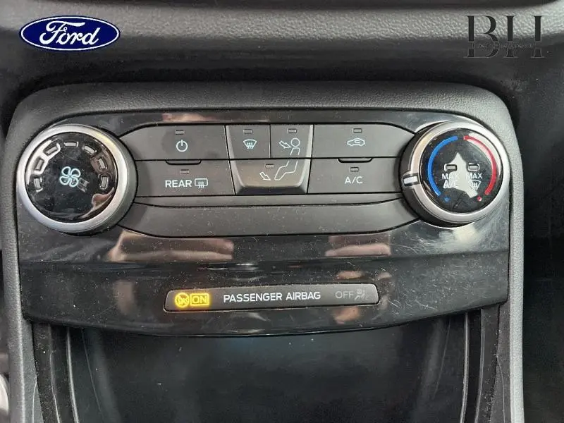 Vue rapprochée de la console centrale du Ford Puma 2022 gris Solar, montrant les commandes de climatisation et l'indicateur airbag passager activé.