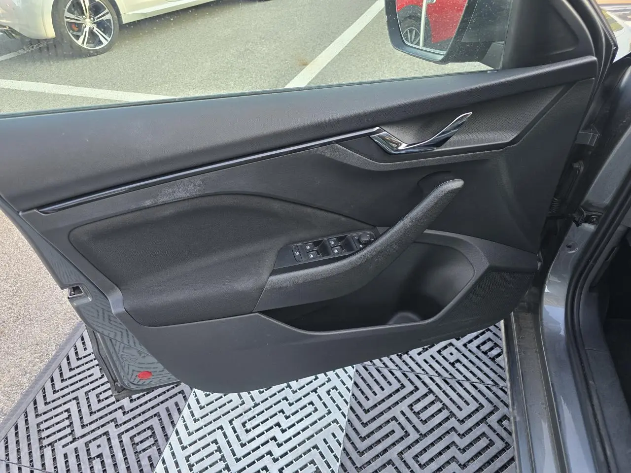 Vue intérieure côté gauche de la porte avant gris graphite métal de la Skoda Scala avec commandes des vitres et poignée chromée.