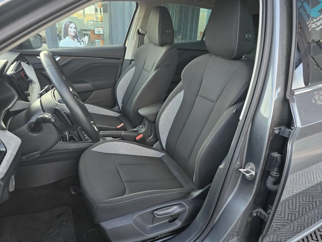 Vue intérieure côté conducteur de la Skoda Scala 2024 gris graphite, sièges tissu noir et gris avec surpiqûres blanches.