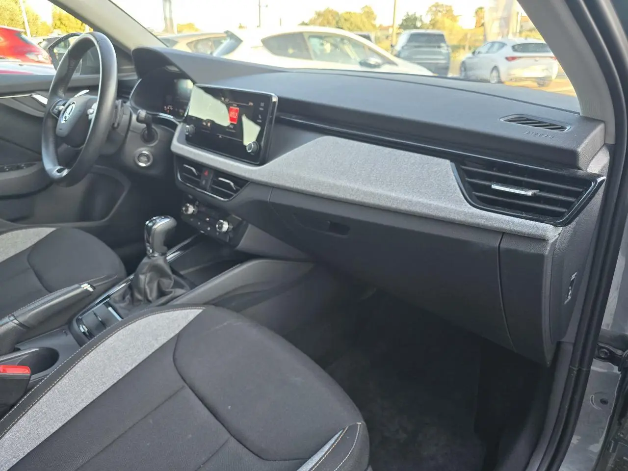 Vue intérieure côté passager de la Skoda Scala gris graphite, montrant tableau de bord et console centrale moderne.