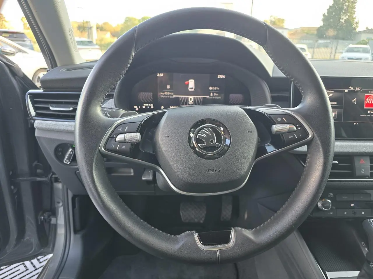 Vue intérieure centrée sur le volant noir de la Skoda Scala 2024 avec tableau de bord digital et écran tactile.