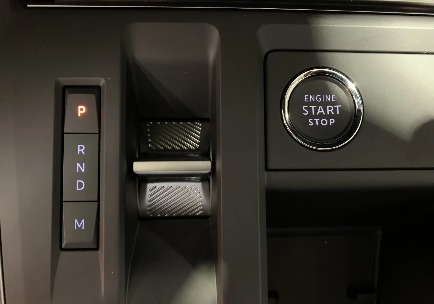 Gros plan sur la console centrale noire du Citroën C5 Aircross hybride 2024 avec bouton Drive Mode et frein à main électronique rouge.