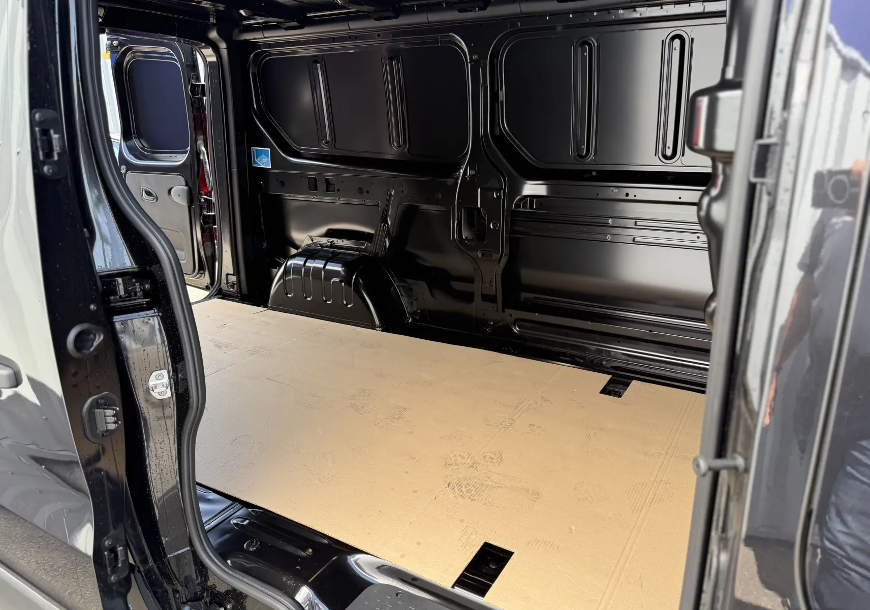 Intérieur du fourgon Renault Trafic noir crépuscule, vue latérale gauche sur l'espace de chargement vide et plancher beige.