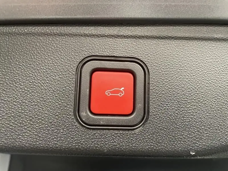 Bouton rouge de déverrouillage du hayon sur le tableau de bord noir texturé d'une Jeep Avenger 2025.