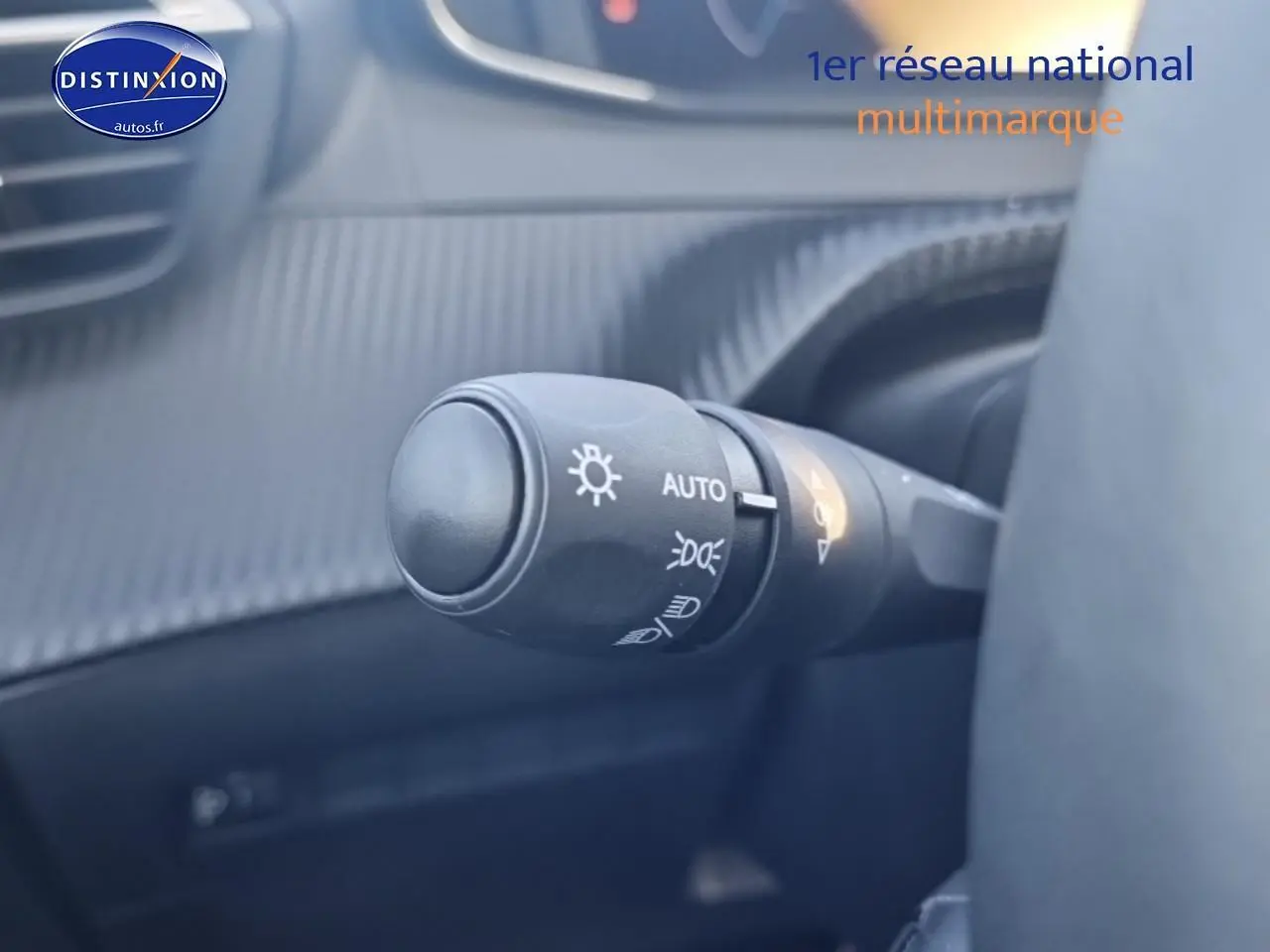 Gros plan sur la commande des phares automatique dans l’habitacle gris d’une Peugeot 208 1.2 100 Allure 2025.